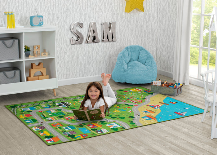 Child reading a book on a colorful rug in a room with a 'SAM' sign on the wall.