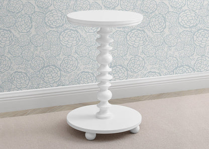 White side table with decorative design on a light-colored floor and patterned wall.