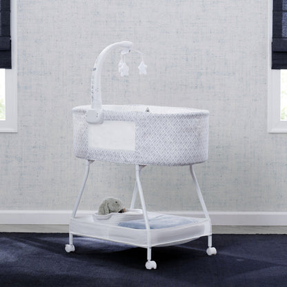 White crib with gray textured cover in a room with gray walls and dark carpet.